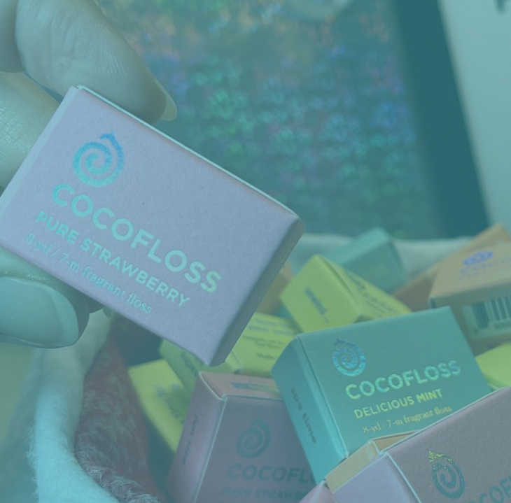 Cocoloss dental product boxes displayed on teal surface with branding visible.
